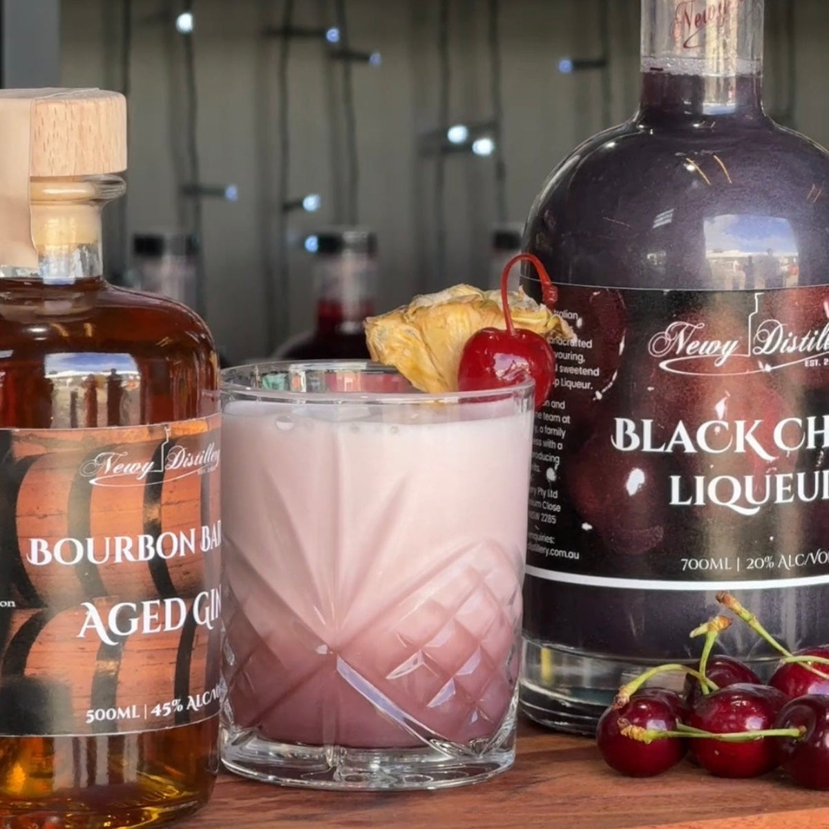 Beverage with garnishes on a wooden surface, surrounded by liquor bottles.
