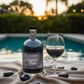 Bottle of liquor and glass by a pool with sunset background
