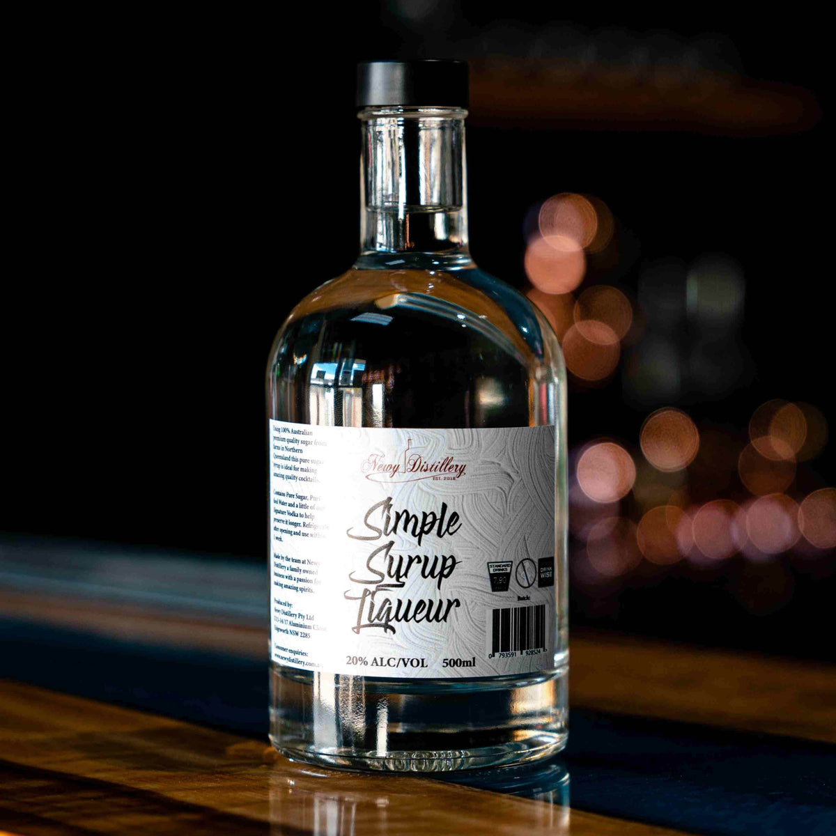 Newy Distillery Simple Syrup Liqueur. Simple syrup for making cocktails. 500ml bottle displayed on bar ledge. Dark background.. 20% alc/vol.