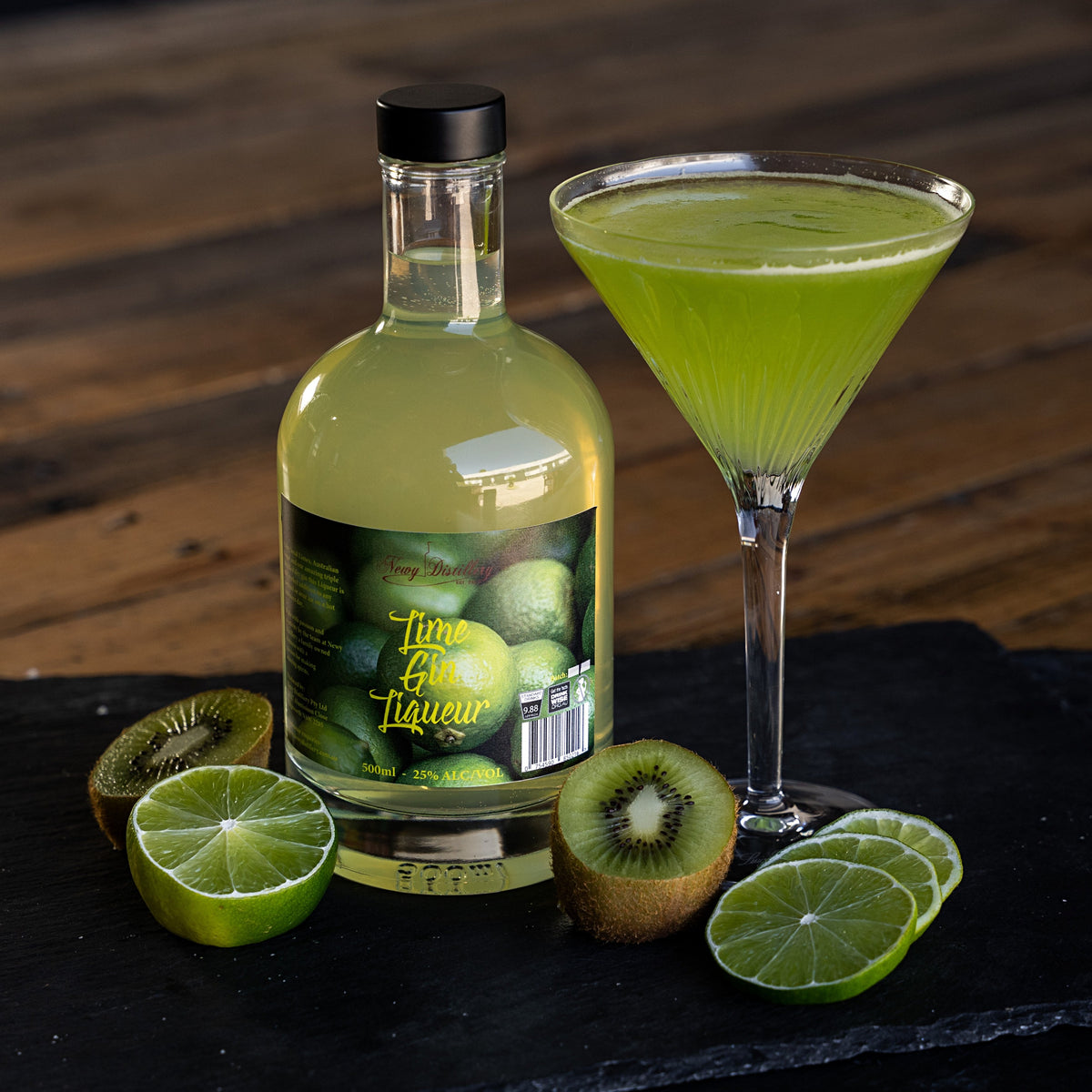 Lime Gin Liqueur 500ml displayed on grey slate next to mango cocktail with fresh Lime garnish. Lime Gin Liqueur, fruit gin liqueur by Newy Distillery.