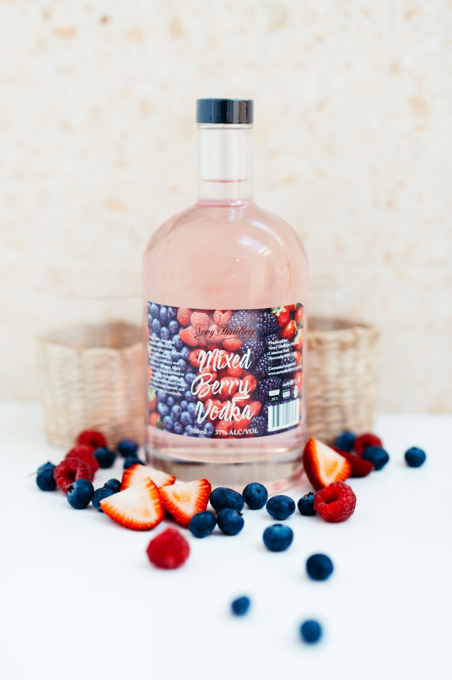 Mixed Berry Fruit Infused Vodka by Newy Distillery. 700ml bottle. Served on wooden board with fresh strawberries, raspberries and blueberries.